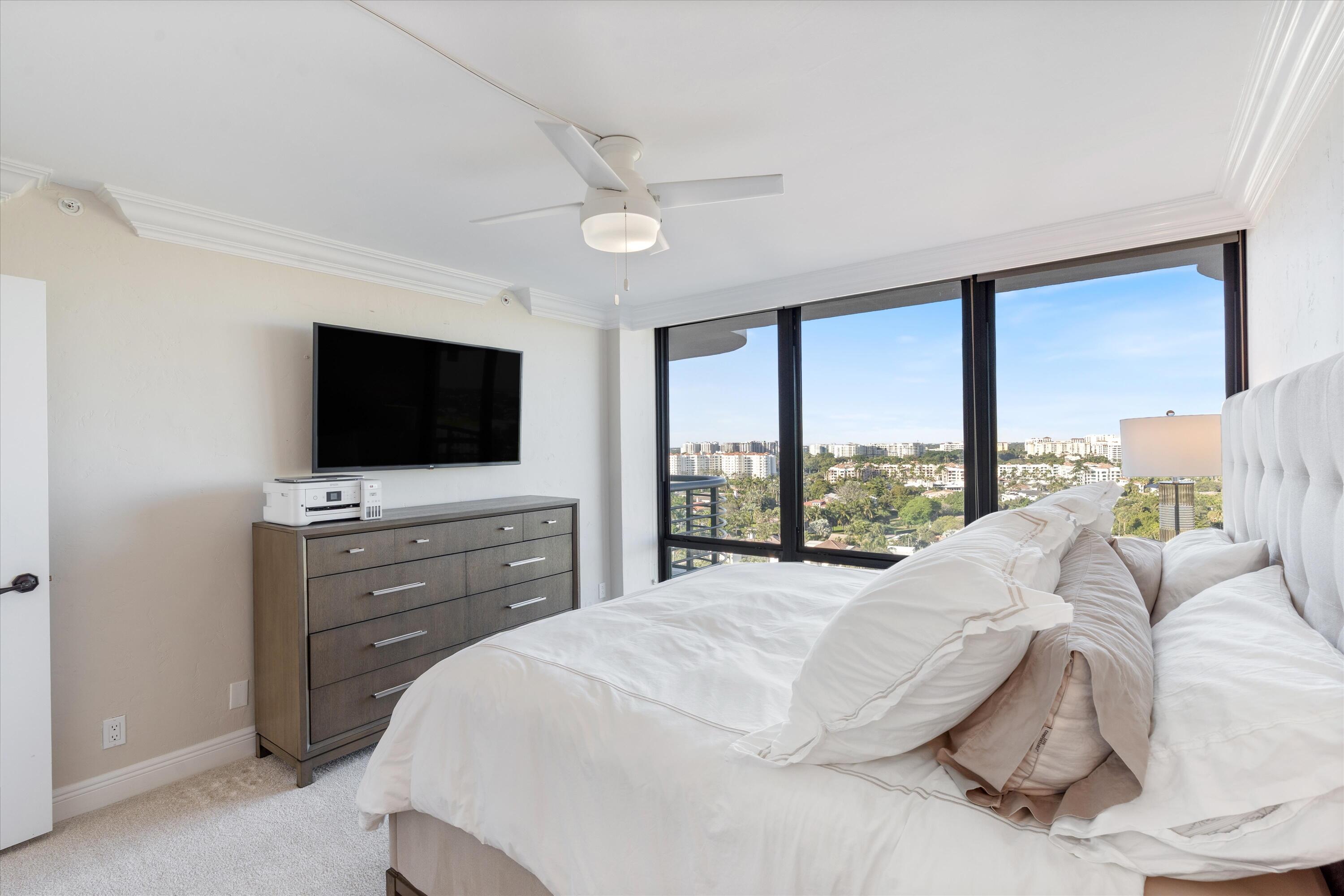 250 South Ocean Boulevard, Unit 14E Boca Raton, FL 33432 - Photo 16 of 27 a large white bed in a large room and a flat screen tv