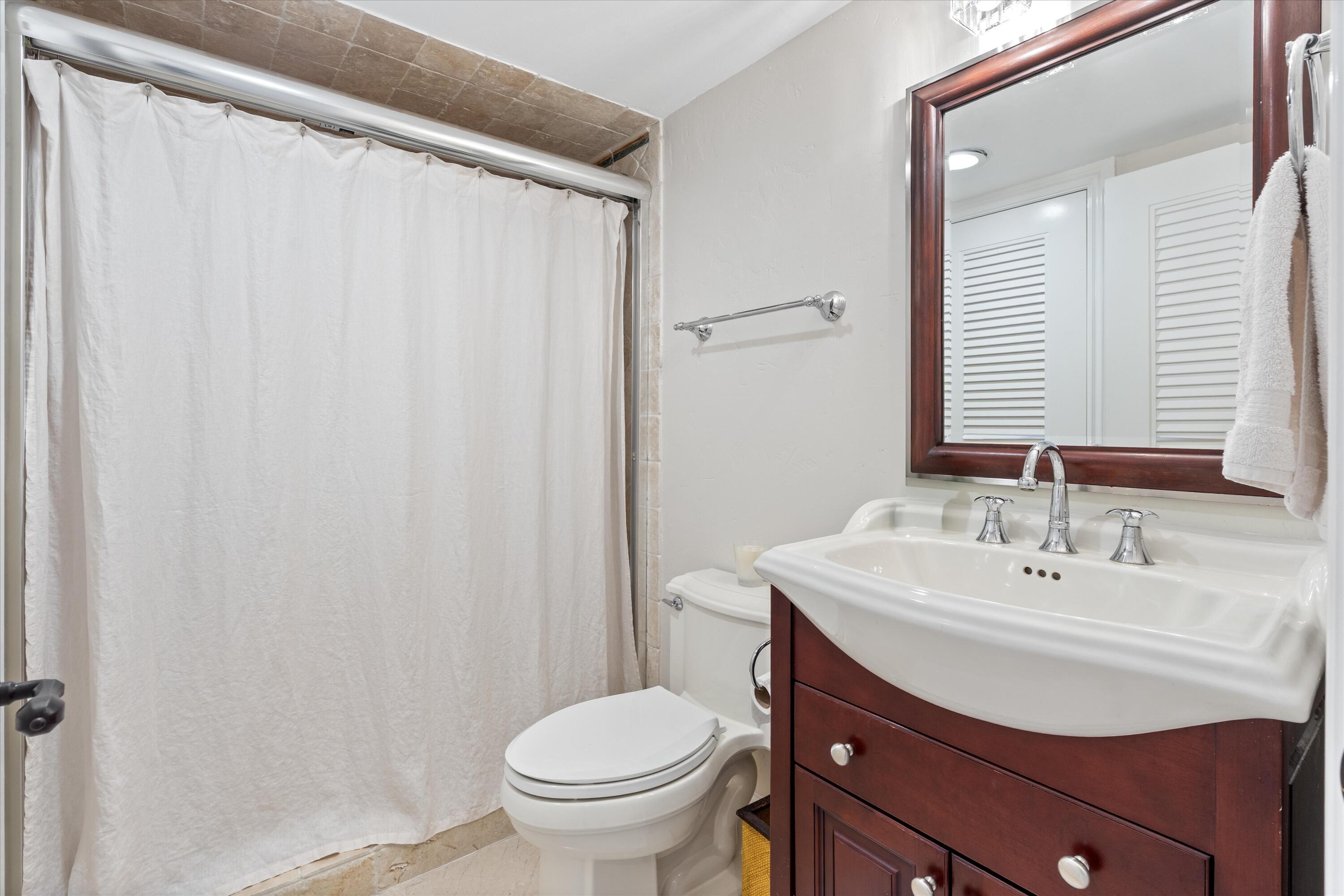 250 South Ocean Boulevard, Unit 14E Boca Raton, FL 33432 - Photo 18 of 27 a bathroom with a sink toilet and a mirror