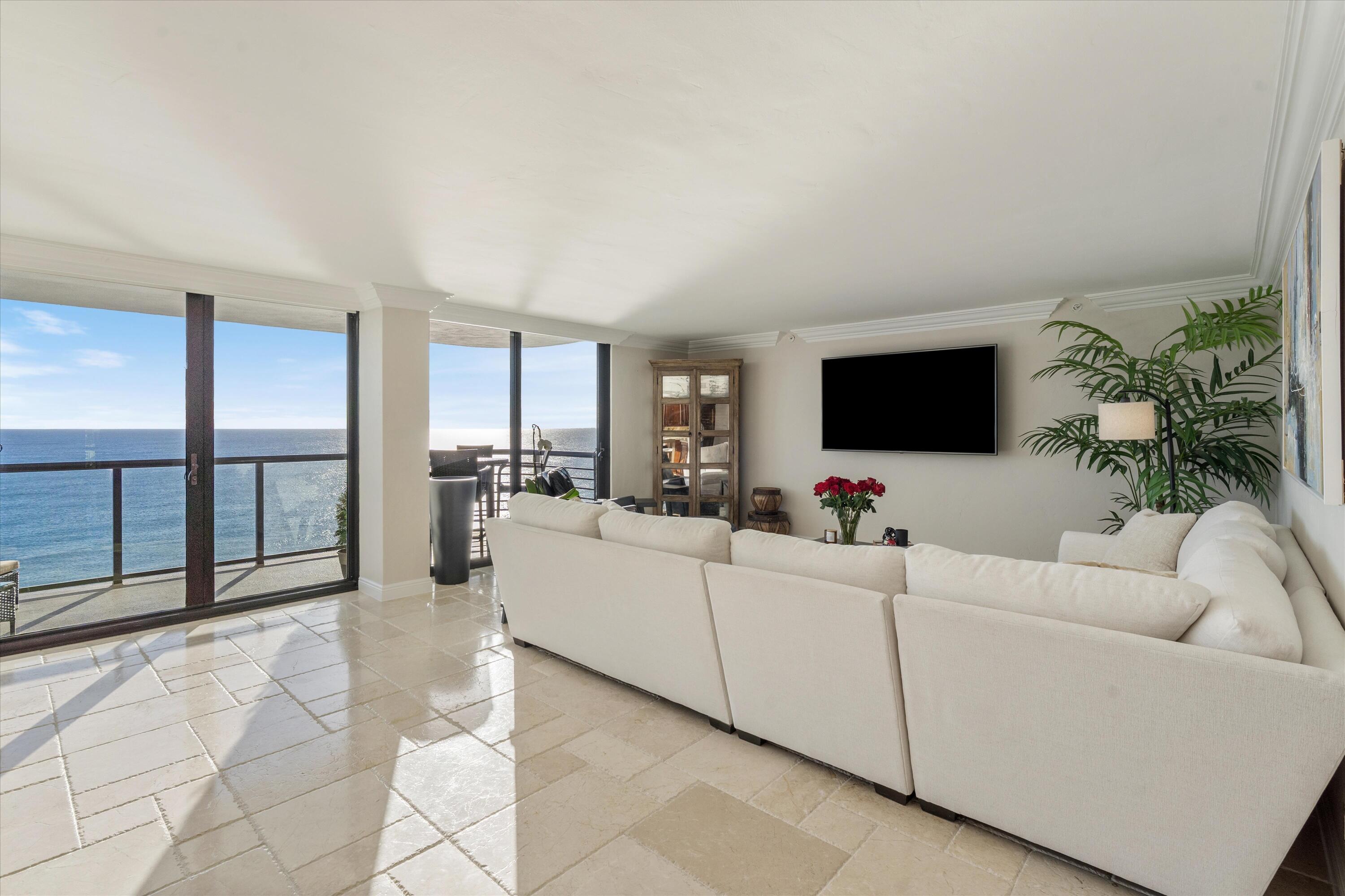 250 South Ocean Boulevard, Unit 14E Boca Raton, FL 33432 - Photo 4 of 27 a living room with furniture a flat screen tv and a floor to ceiling window