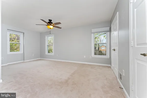 an empty room with windows and a chandelier fan