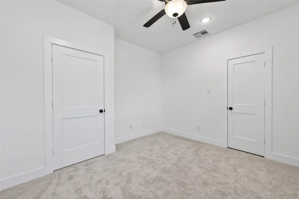 an empty room with a ceiling fan and carpet