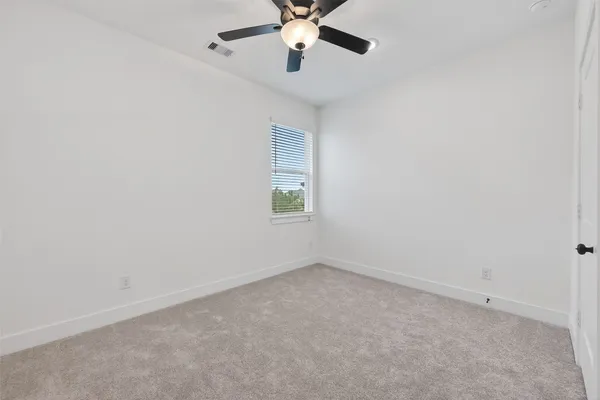 an empty room with a window and a fan