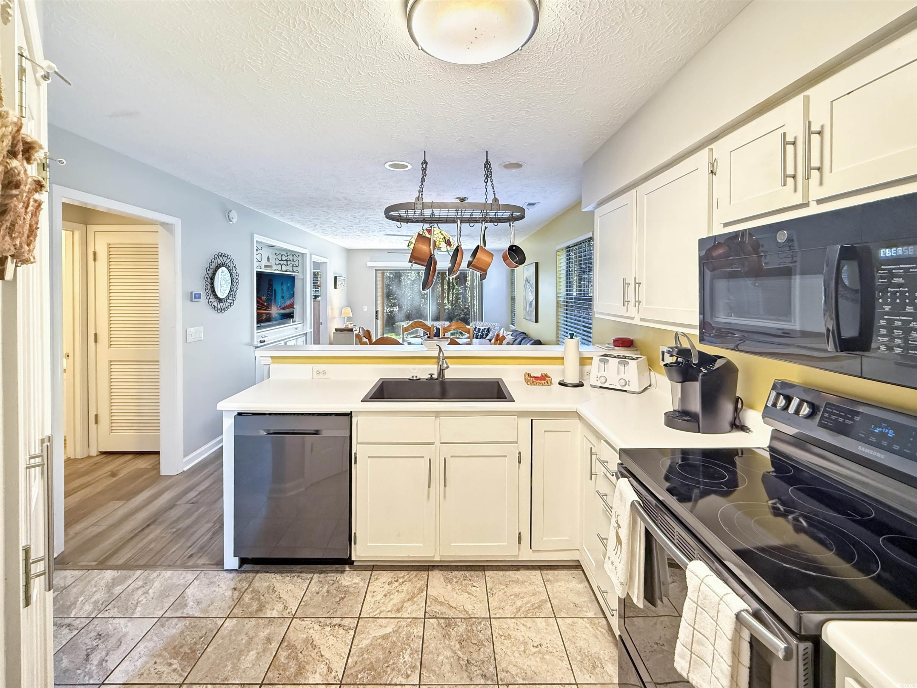227 Pinehurst Lane, Unit 6D Pawleys Island, SC 29585 - Photo 25 of 39 Kitchen featuring a peninsula, appliances with stainless steel finishes, a textured ceiling, white cabinets, and light countertops