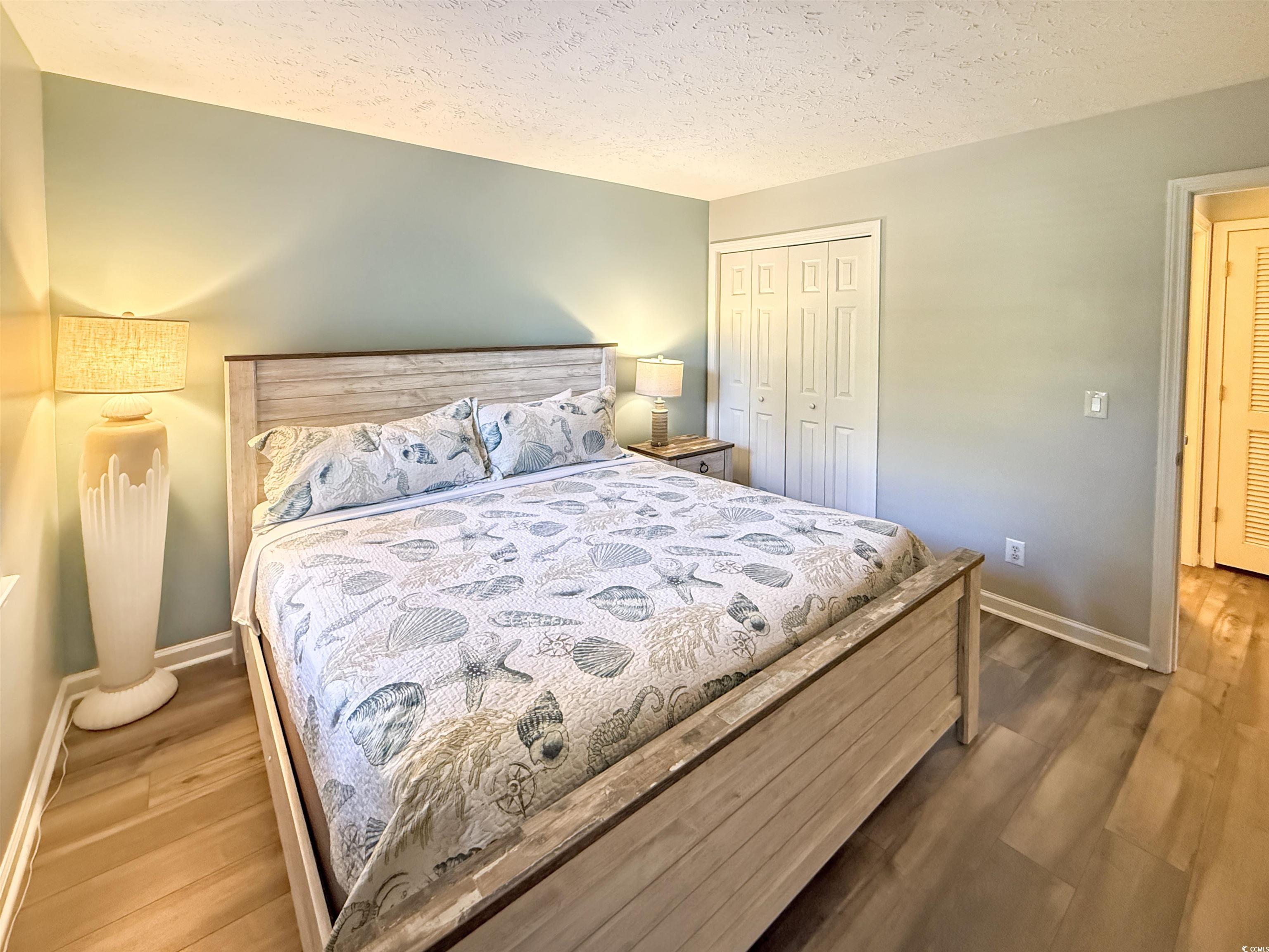 227 Pinehurst Lane, Unit 6D Pawleys Island, SC 29585 - Photo 30 of 39 Bedroom with a textured ceiling, a closet, and wood finished floors