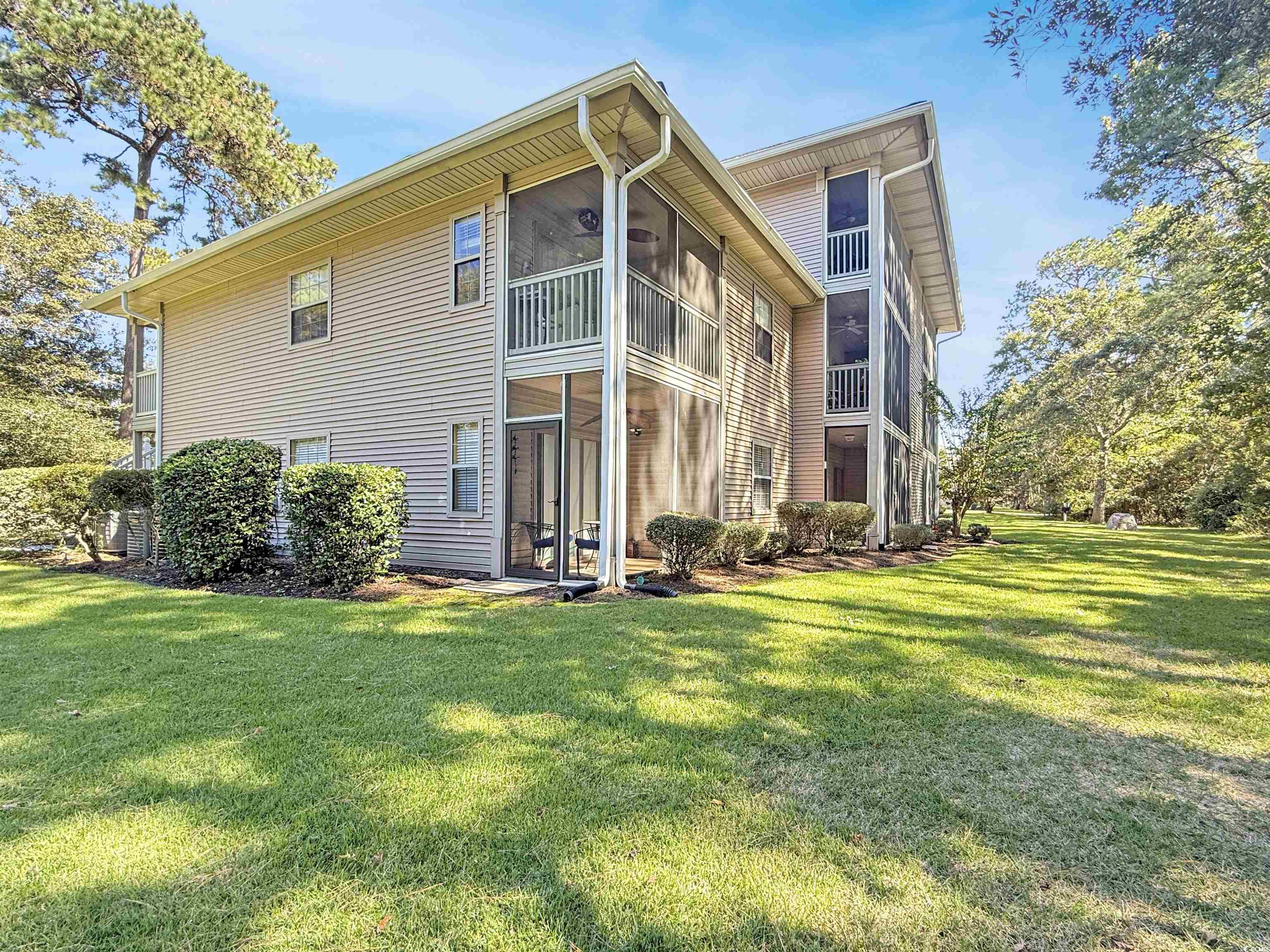 227 Pinehurst Lane, Unit 6D Pawleys Island, SC 29585 - Photo 36 of 39 Rear view of property with a sunroom, a lawn, and a balcony