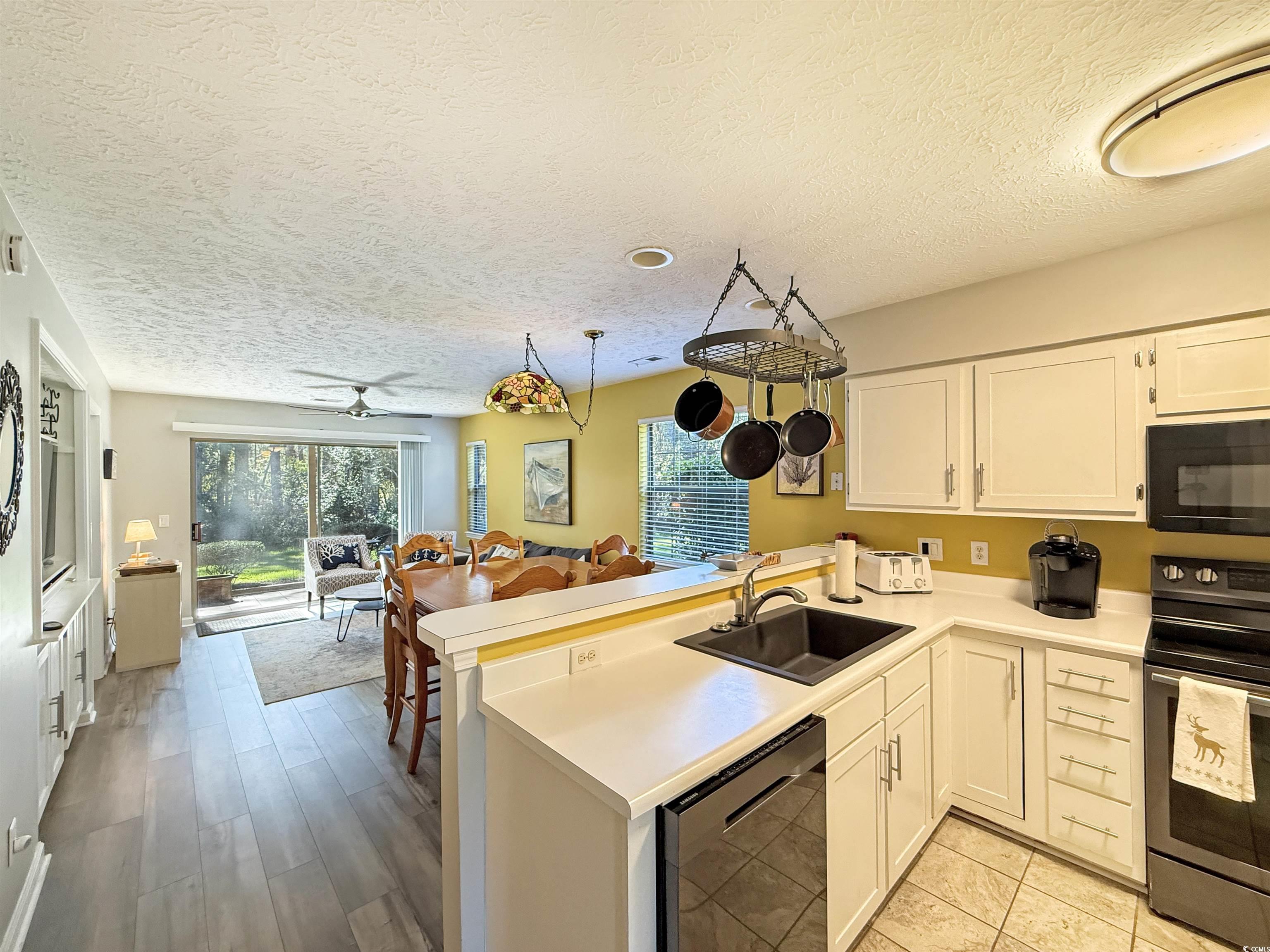 227 Pinehurst Lane, Unit 6D Pawleys Island, SC 29585 - Photo 5 of 39 Kitchen featuring black appliances, a peninsula, light countertops, white cabinets, and a textured ceiling