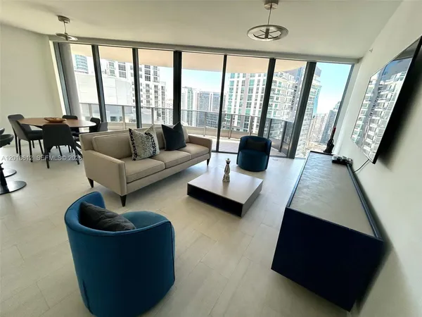 a living room with furniture and floor to ceiling windows