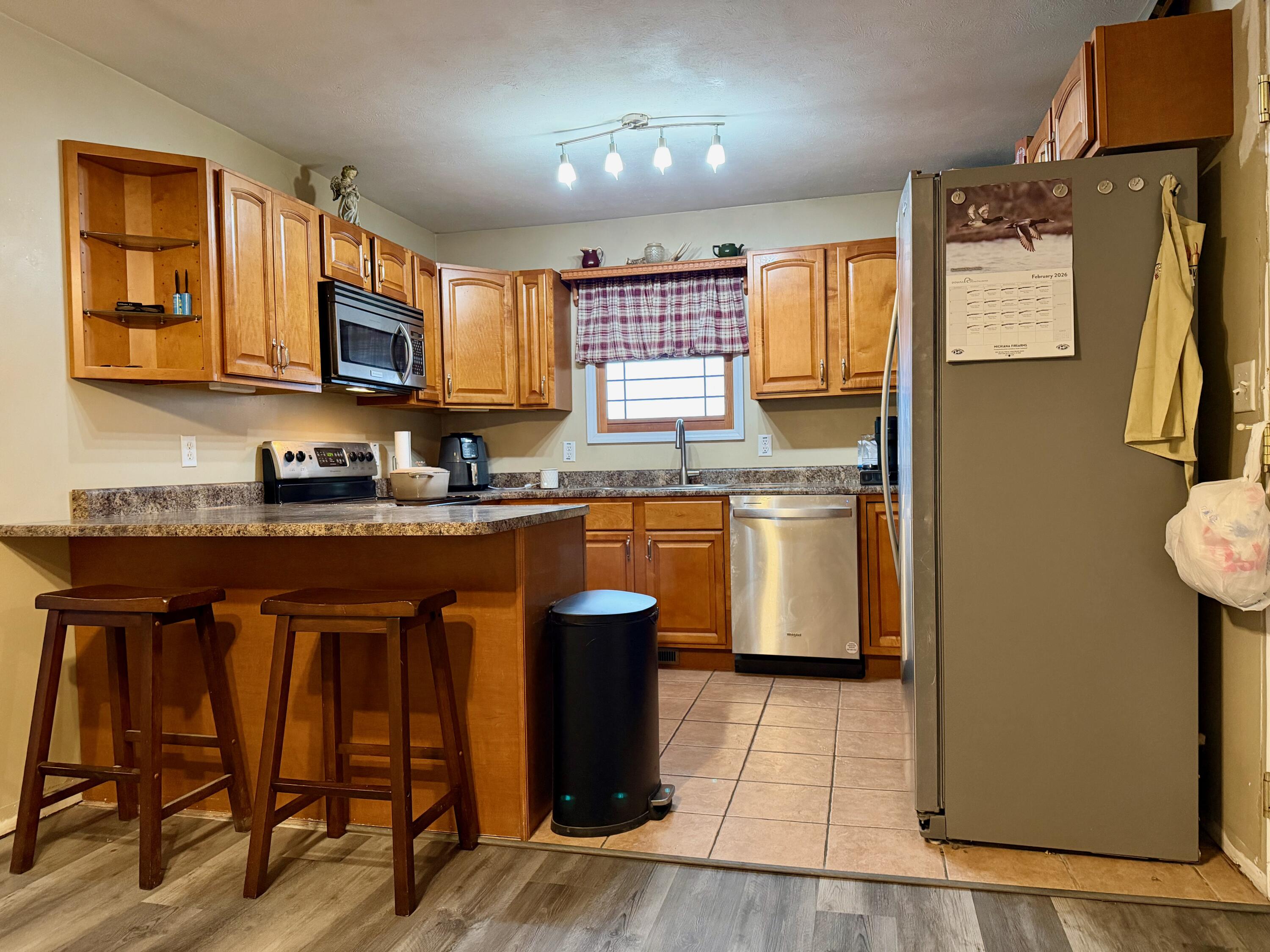5850 West 600 North Winamac, IN 46996 - Photo 5 of 28 a kitchen with stainless steel appliances granite countertop wooden cabinets a sink a stove a dining table and chairs