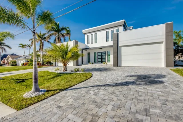 a view of a house with small yard plants and palm trees