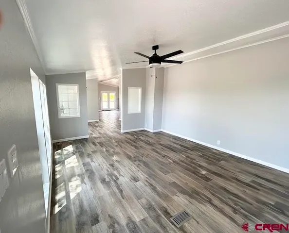 a view of empty room with wooden floor and fan