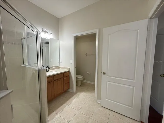 a bathroom with a glass door shower a sink and a toilet