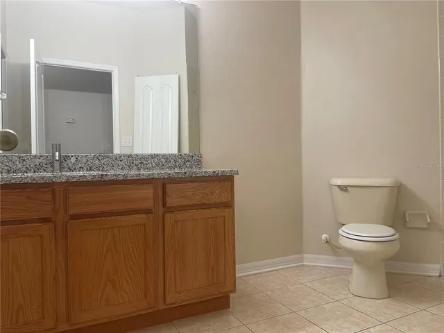 a bathroom with a granite countertop sink and a toilet