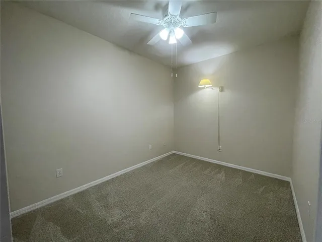 an empty room with a fan & a window