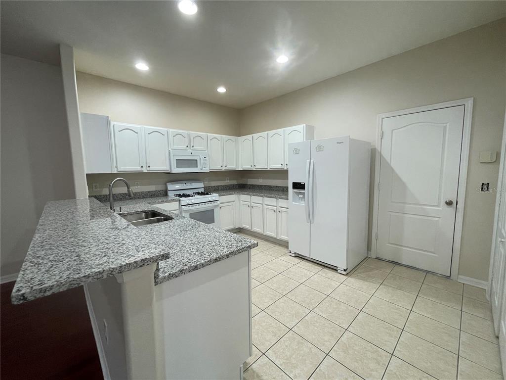 1228 Bensbrooke Drive Wesley Chapel, FL 33543 - Photo 7 of 37 a kitchen with stainless steel appliances granite countertop a sink stove and refrigerator