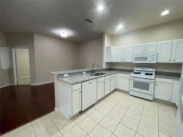 a white kitchen with granite countertop a sink
