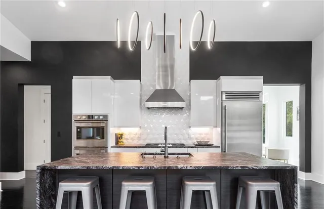 a kitchen with stainless steel appliances a table chairs in it and wooden floors