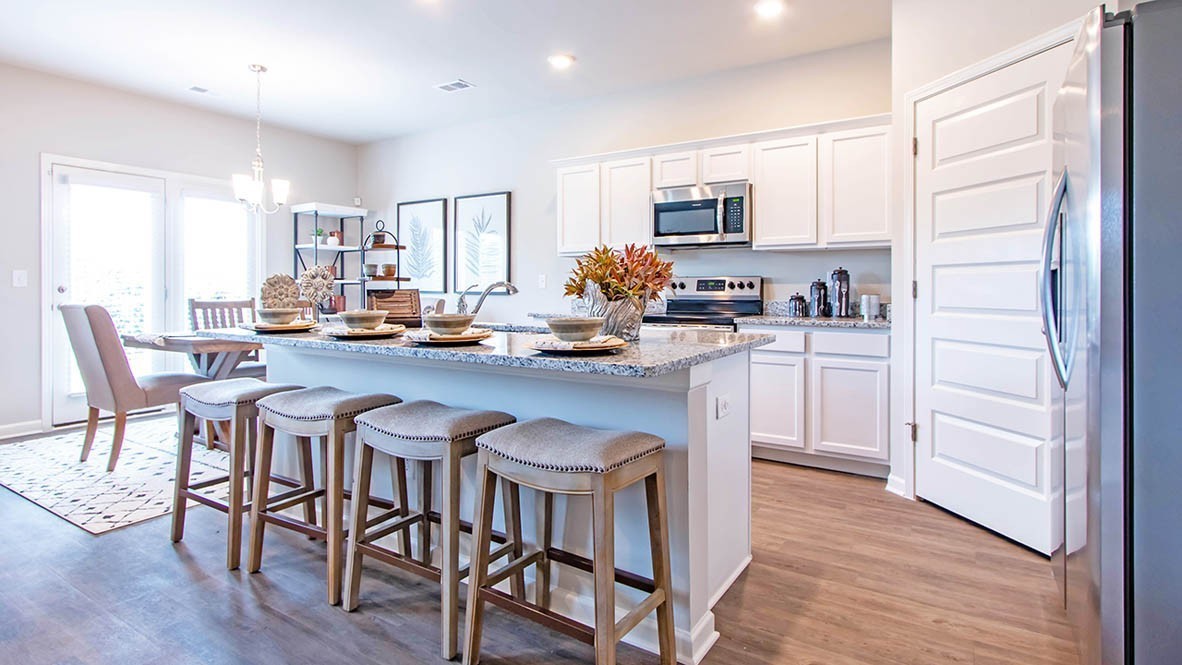 a kitchen with stainless steel appliances granite countertop a table chairs microwave and sink
