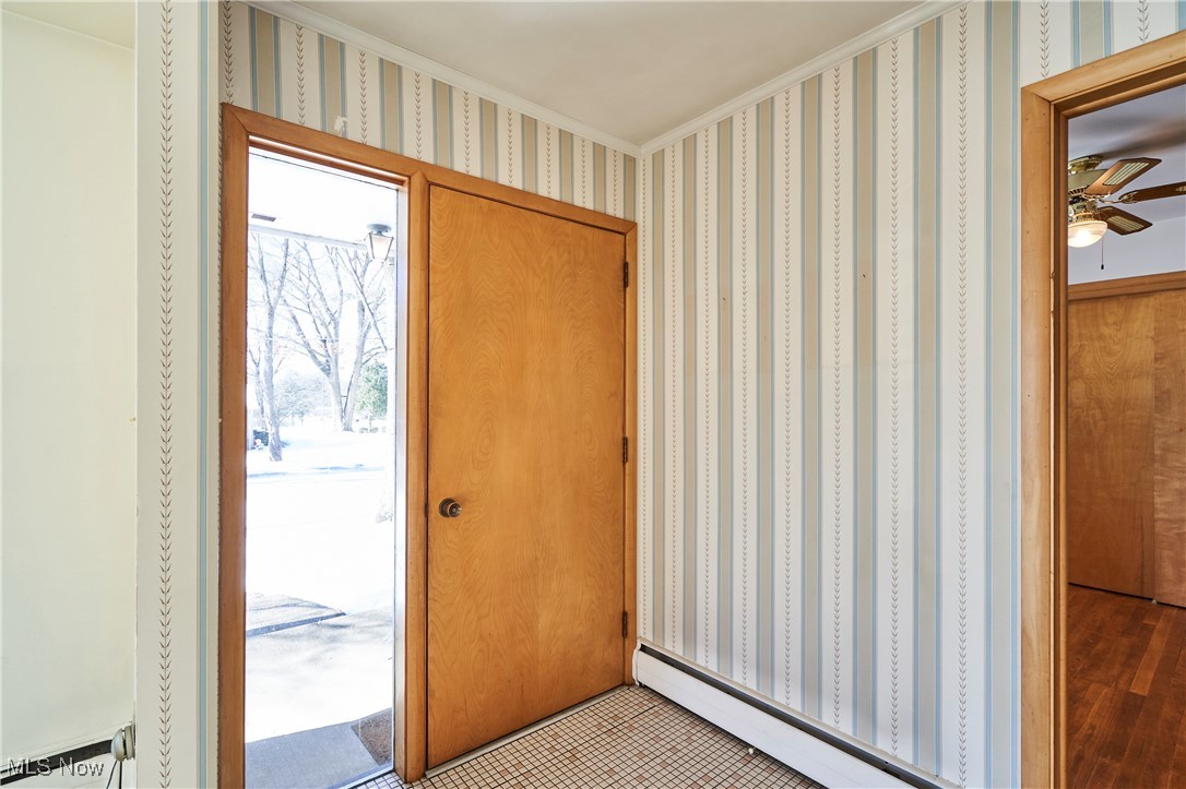 Entrance foyer with crown molding and a baseboard heating unit