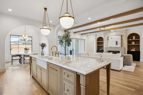 a open kitchen with stainless steel appliances granite countertop a stove top oven a sink dishwasher a dining table and chairs with wooden floor