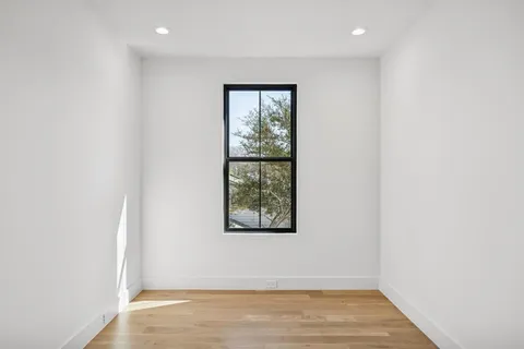 an empty room with wooden floor and window