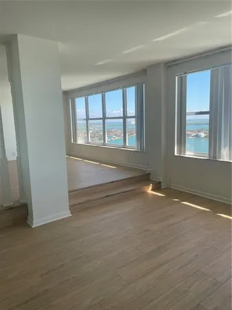 a view of an empty room with wooden floor and fan