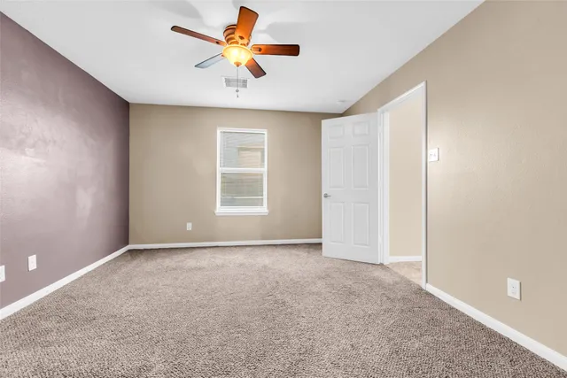a view of an empty room with window and a ceiling fan