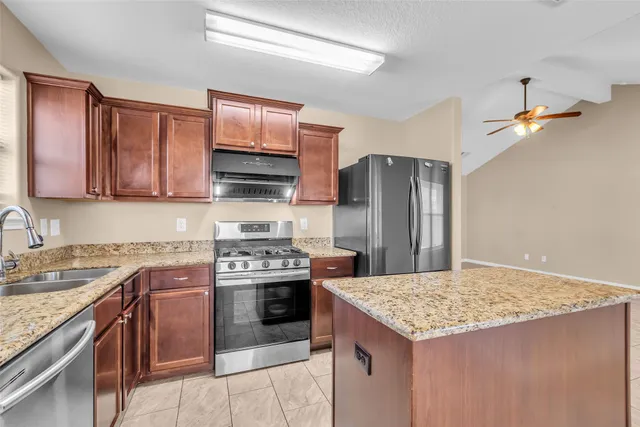 a kitchen with stainless steel appliances granite countertop a stove refrigerator sink and microwave