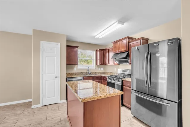 a kitchen with stainless steel appliances granite countertop a refrigerator stove and sink