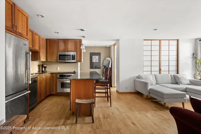 a kitchen with a refrigerator a stove top oven a sink dishwasher and furniture with wooden floor