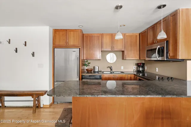 a kitchen with granite countertop a sink a stove and refrigerator