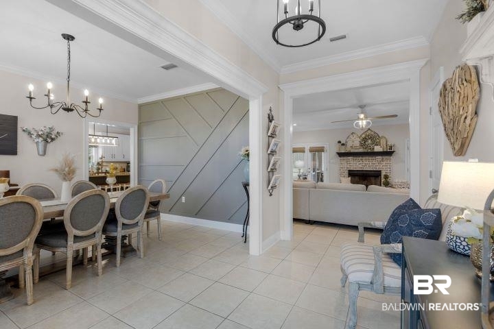 24541 Baldwin Beach Expressway Robertsdale, AL 36567 - Photo 14 of 51 Dining space with light tile patterned floors, ornamental molding, ceiling fan with notable chandelier, visible vents, and a fireplace