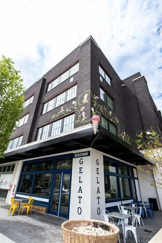 a front view of a building with potted plants and a bench