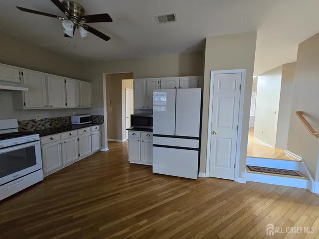 a kitchen with granite countertop a refrigerator and a stove top oven