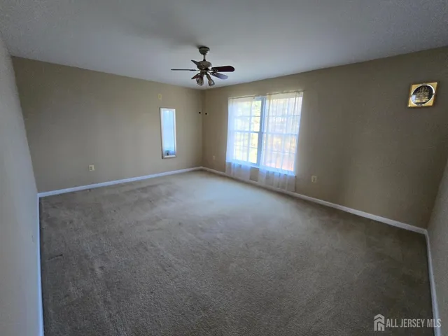 en empty room with windows and ceiling fan