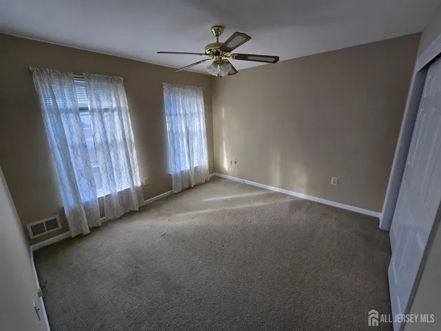 an empty room with windows and fan