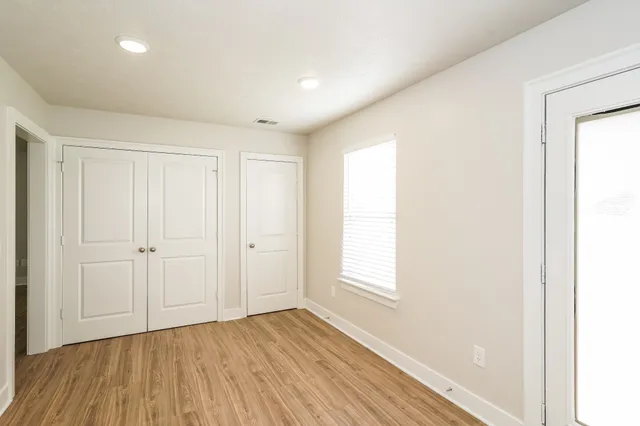 an empty room with wooden floor and windows