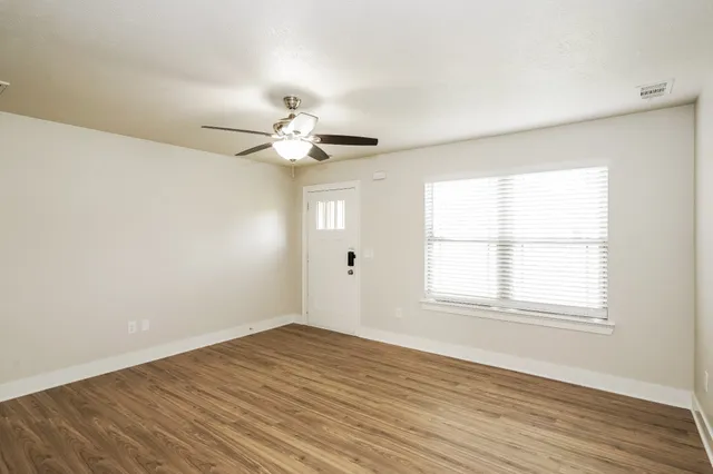 an empty room with wooden floor and windows