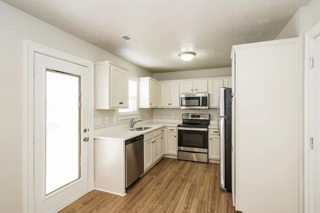 a kitchen with stainless steel appliances granite countertop a stove top oven a sink and a refrigerator