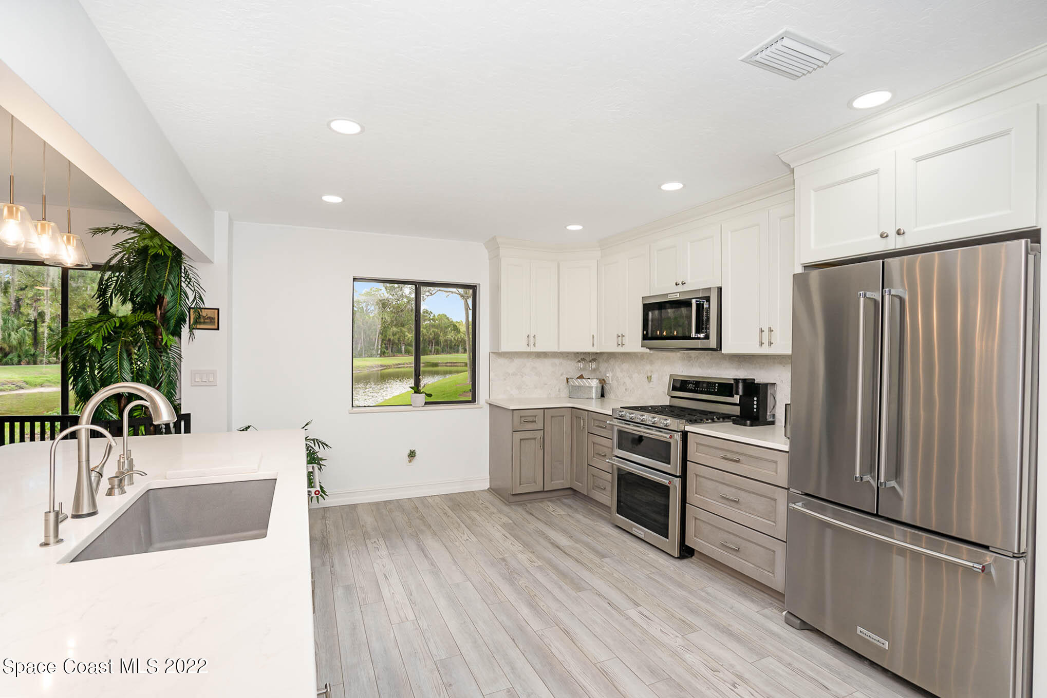1425 Kitty Hawk Way Melbourne, FL 32940 - Photo 23 of 53 a kitchen with stainless steel appliances granite countertop a refrigerator a sink dishwasher a oven with white cabinets and wooden floor