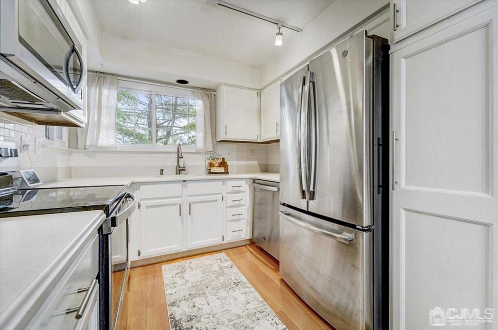 9 Tory Court Bedminster, NJ 07921 - Photo 4 of 26 a kitchen with granite countertop a refrigerator sink and white cabinets