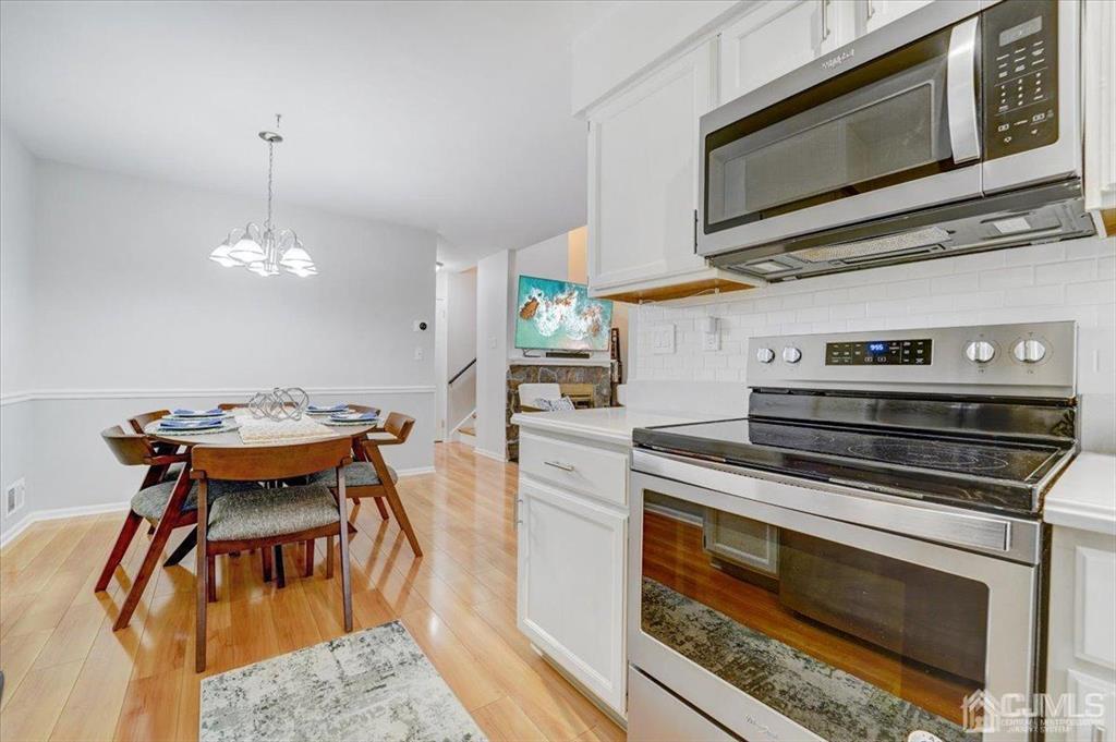 9 Tory Court Bedminster, NJ 07921 - Photo 6 of 26 a kitchen with stainless steel appliances a stove a microwave a dining table and chairs