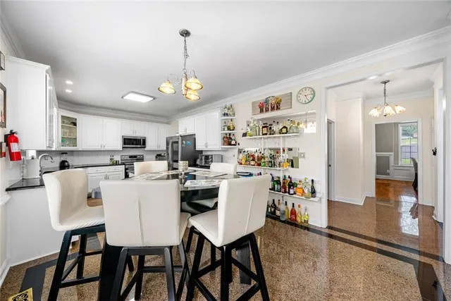 a spacious bedroom with a bed a chandelier and dresser