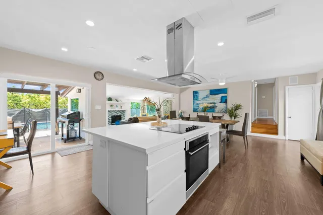 a kitchen with stainless steel appliances a stove a sink a dining table and chairs with wooden floor