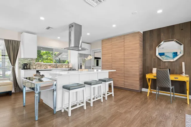 a kitchen with stainless steel appliances kitchen island granite countertop a stove a sink a dining table and chairs