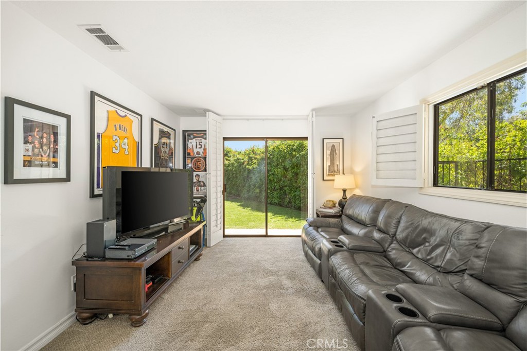 9741 Rangeview Drive North Tustin, CA 92705 - Photo 28 of 48 Fourth Bedroom on the opposite side of this sprawling ranch is perfect for in-laws or guests with patio doors and an adjacent courtyard with shady Califonia pepper tree. The picture is deceiving because of long sofa - room size is 18' x 12' not including the closet with mirrored wardrobe doors.