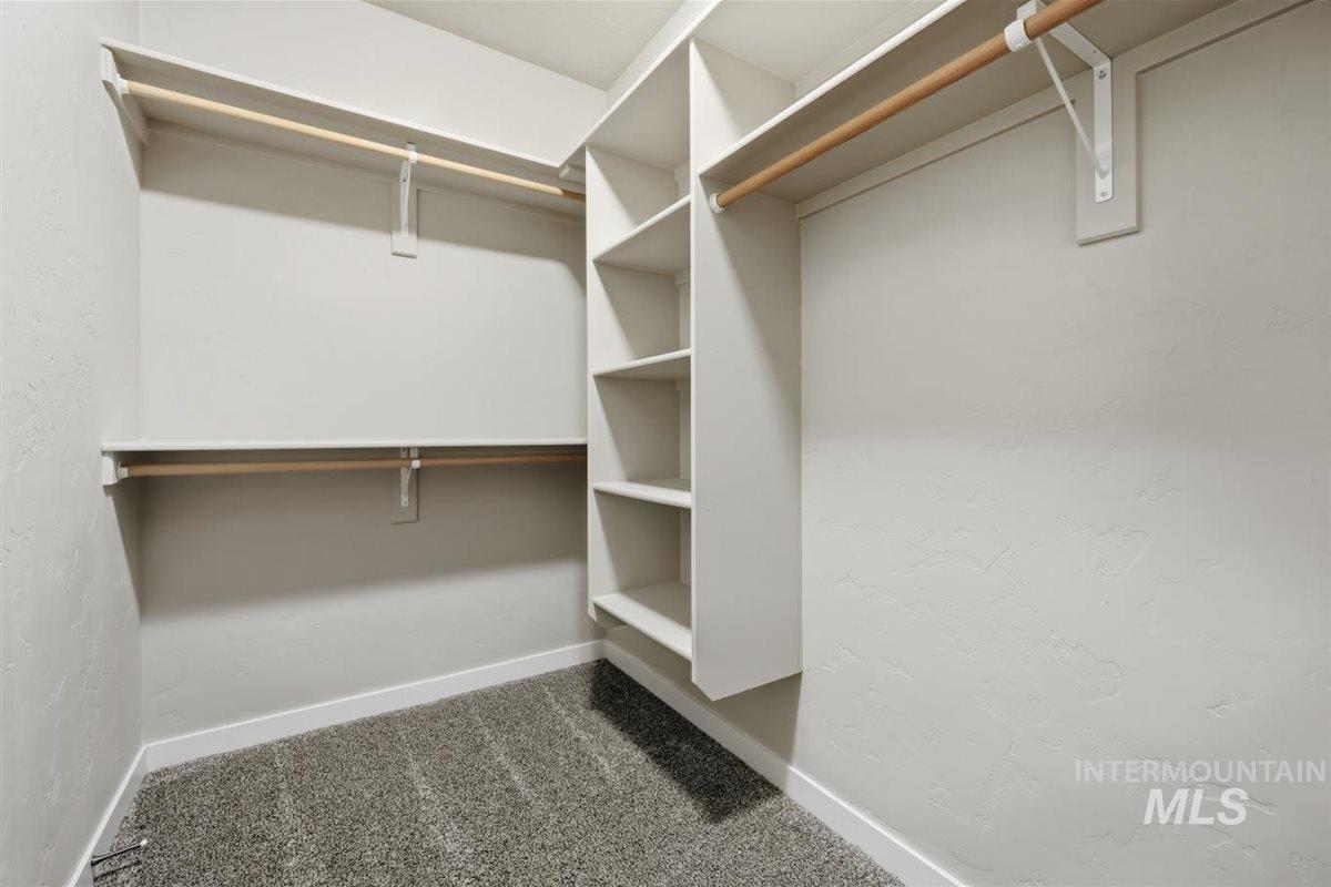 13496 Hockberger Ranch Road Caldwell, ID 83607 - Photo 26 of 40 Walk-in closet featuring built-in shelving, two levels of hanging rods, and textured wall finishes with baseboard trim