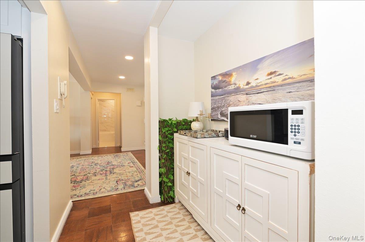 320 East Shore Road, Unit 4C Great Neck, NY 11023 - Photo 14 of 29 Kitchen featuring white microwave, white cabinetry, light countertops, recessed lighting, and freestanding refrigerator