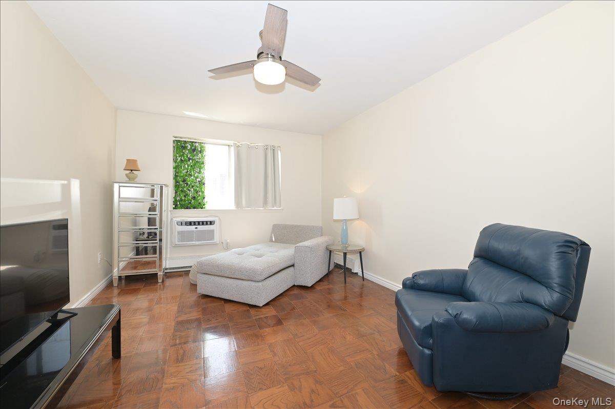 320 East Shore Road, Unit 4C Great Neck, NY 11023 - Photo 17 of 29 Living area with parquet floors, a ceiling fan, and an AC wall unit