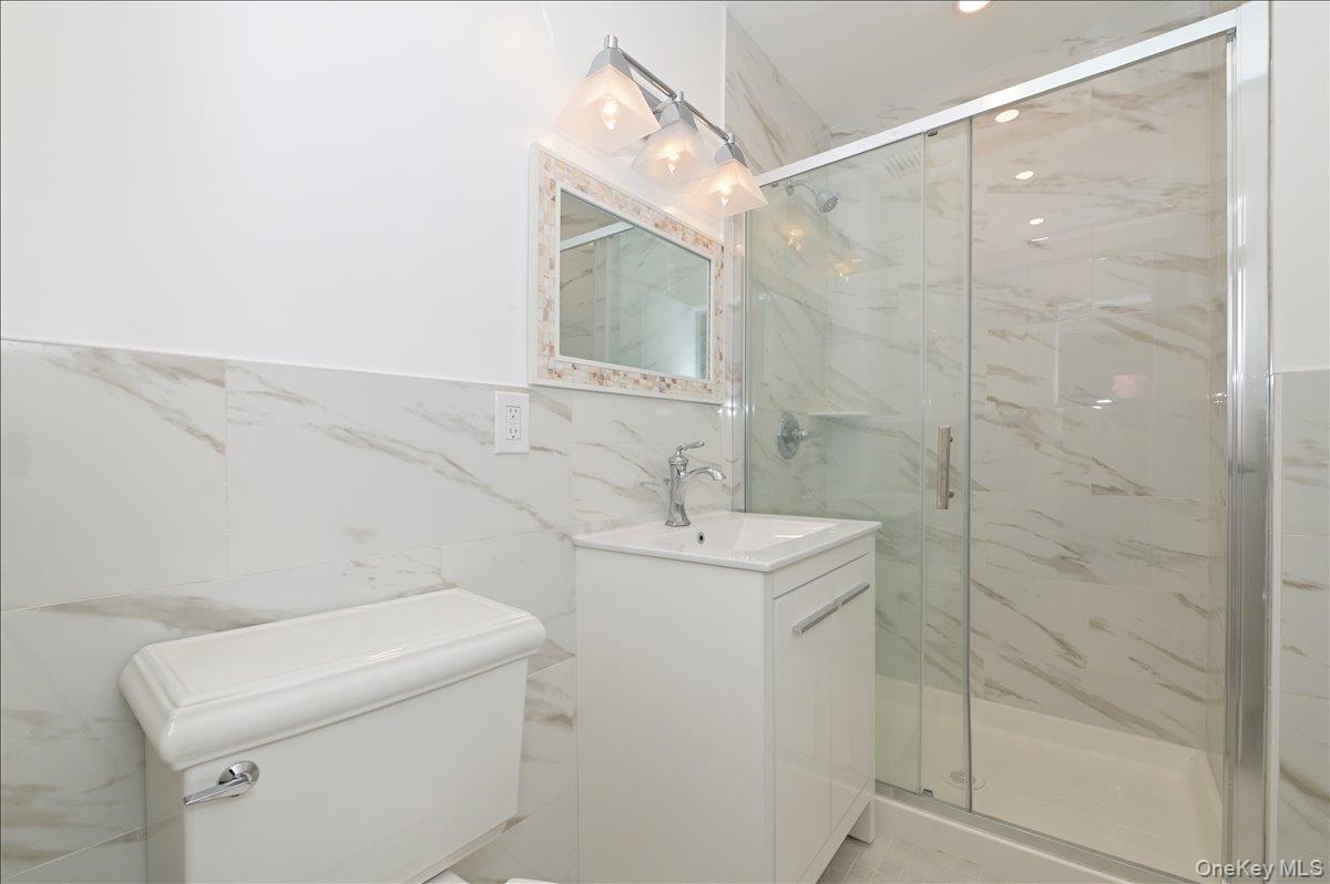 320 East Shore Road, Unit 4C Great Neck, NY 11023 - Photo 18 of 31 Bathroom featuring vanity, a marble finish shower, and tile walls