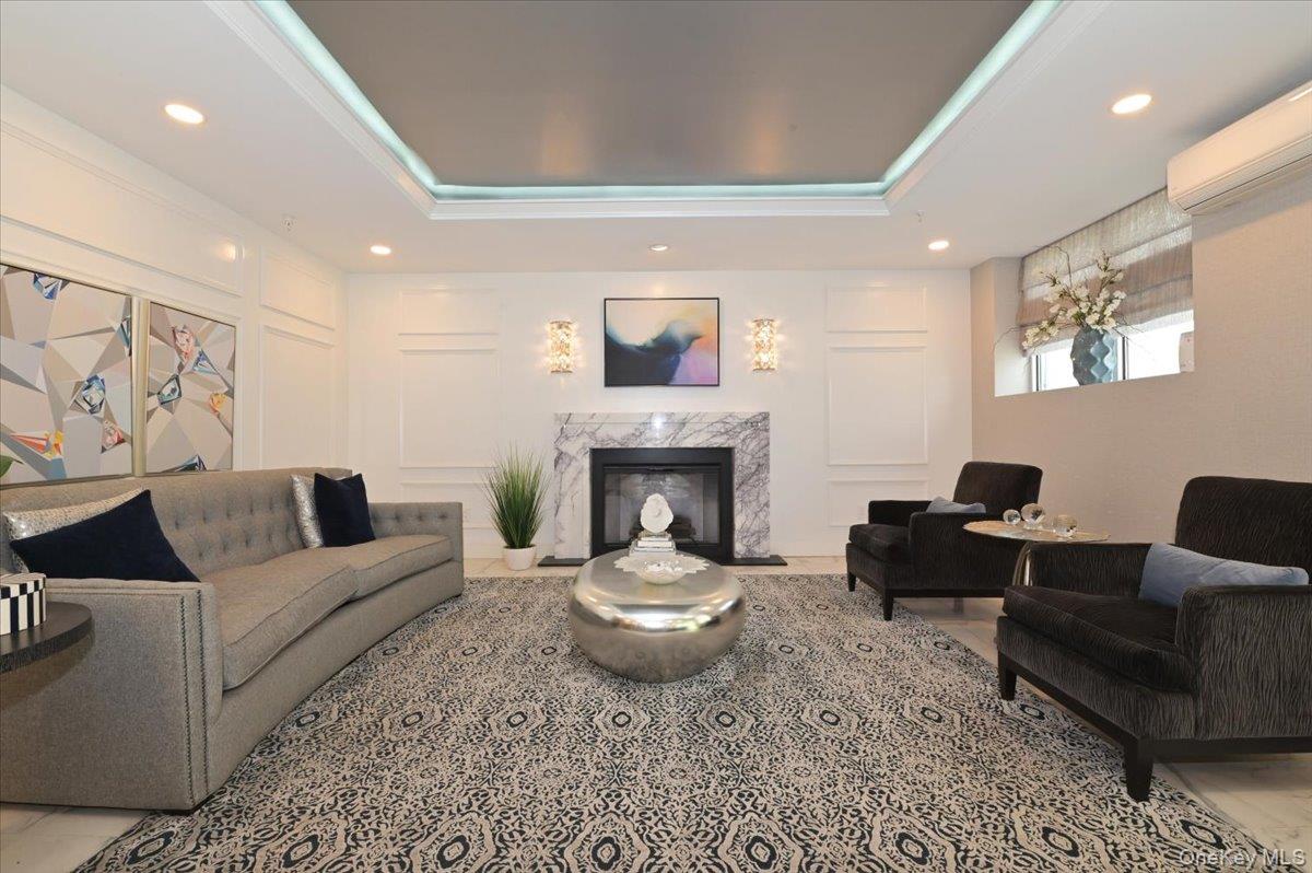 320 East Shore Road, Unit 4C Great Neck, NY 11023 - Photo 5 of 31 Living room featuring a decorative wall, recessed lighting, a tray ceiling, a high end fireplace, and an AC wall unit
